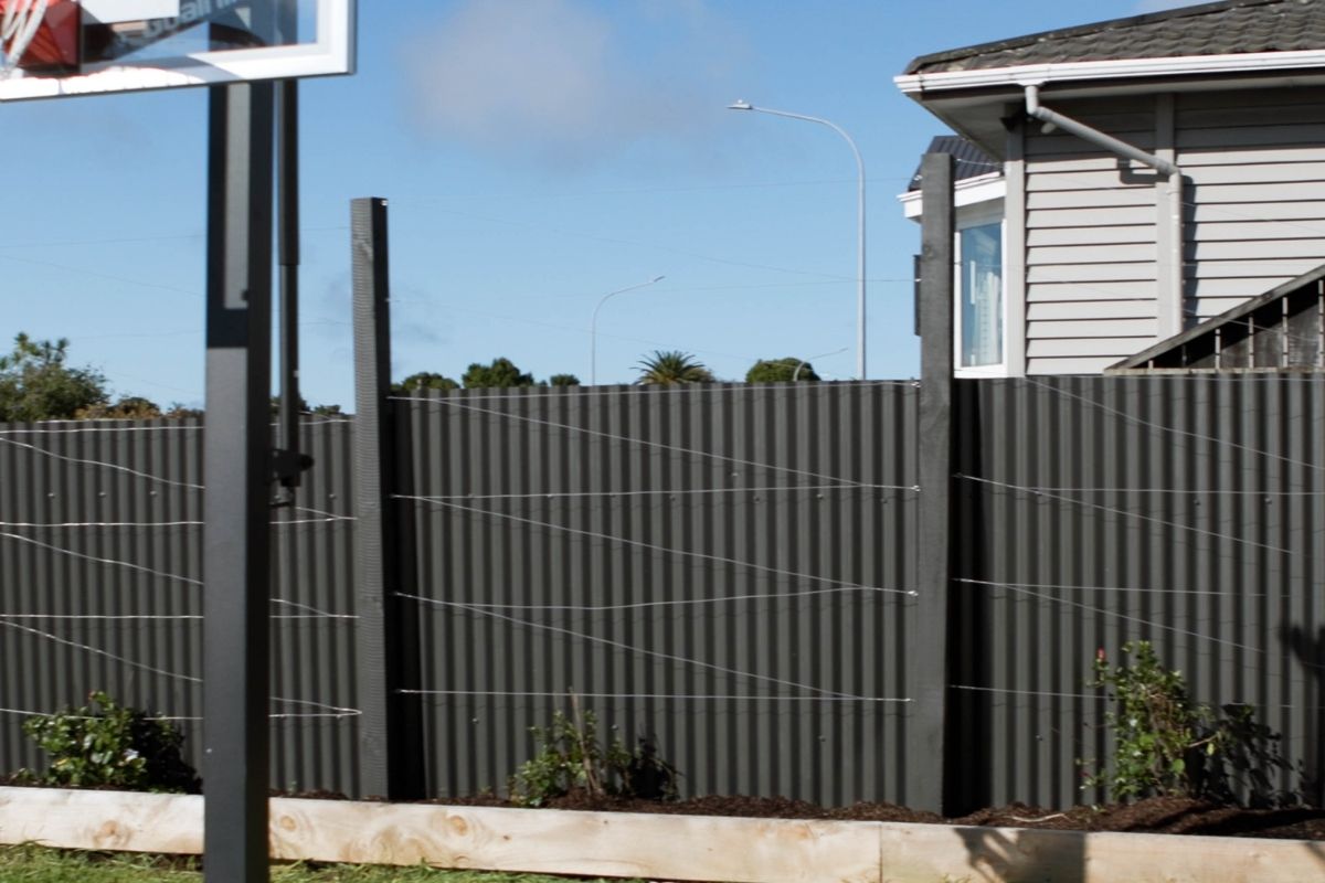 Painted black fence in backyard with basketball ring
