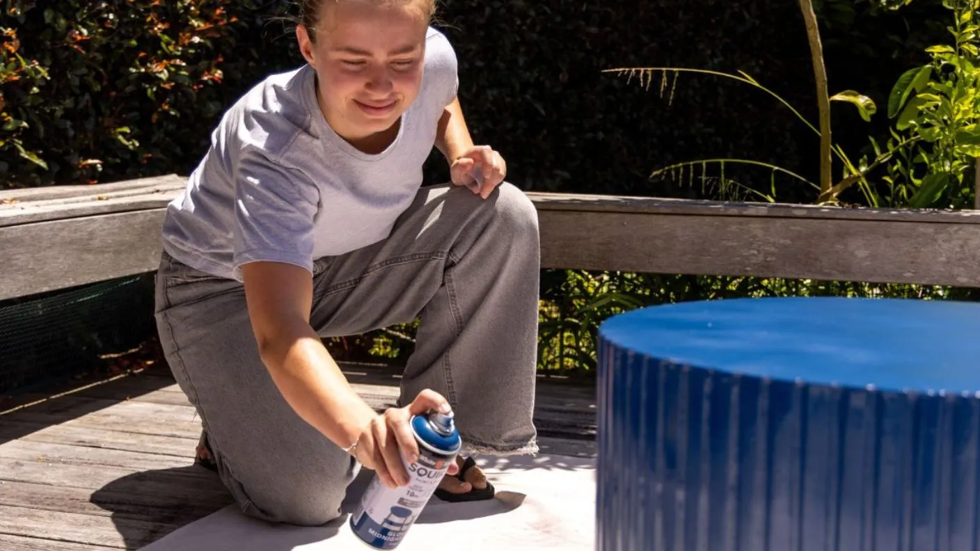 Person using White Knight Squirts in blue to topcoat recycled piece of furniture