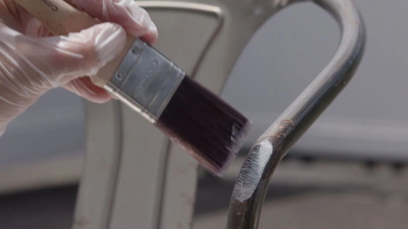 Applying White Knight Rust Guard Rust Converter to rusted area on metal chair