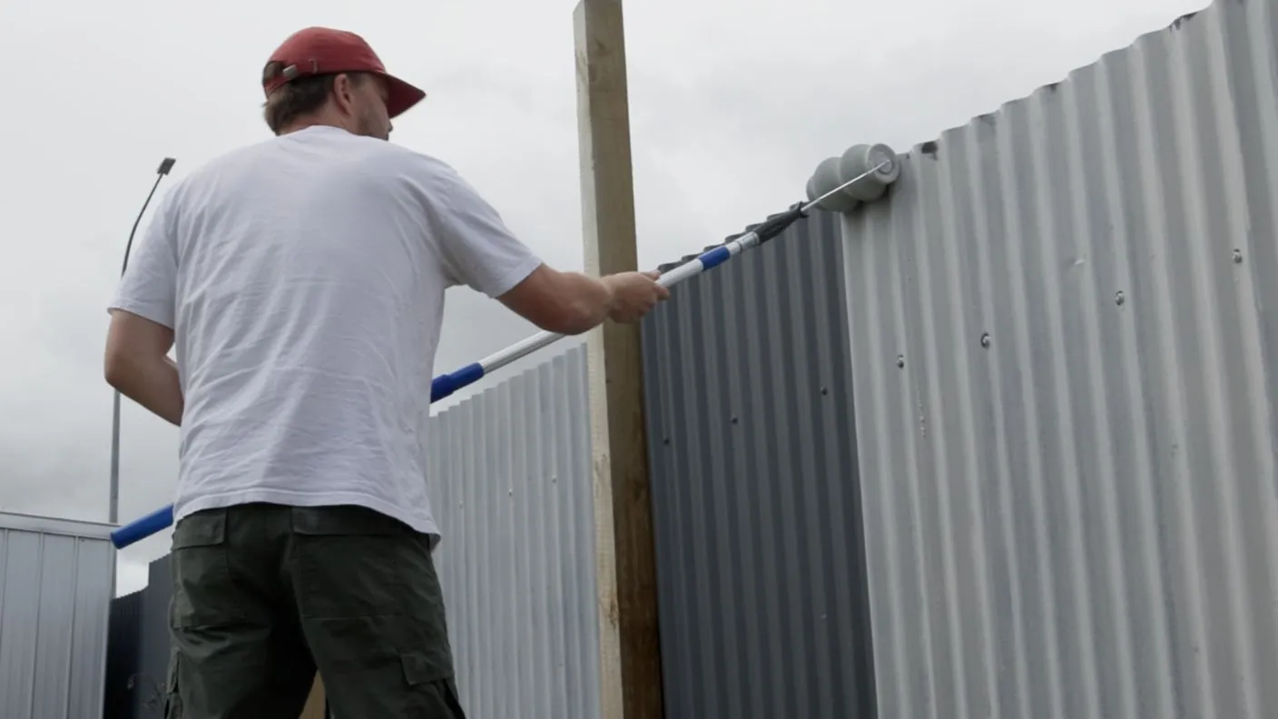 Man applying White Knight True Bite Primer to corrugated fence using corrugated roller
