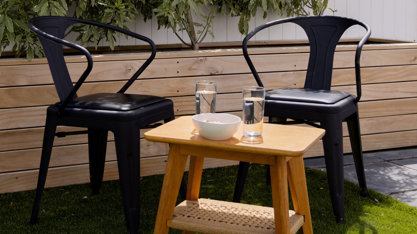 Two metal outdoor chairs painted gloss black with White Knight Rust Guard styled in a garden setting