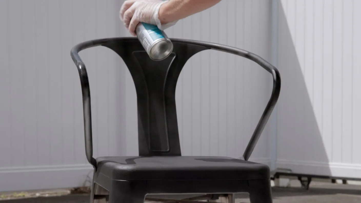 Spraying White Knight Epoxy Enamel black topcoat onto a metal outdoor chair