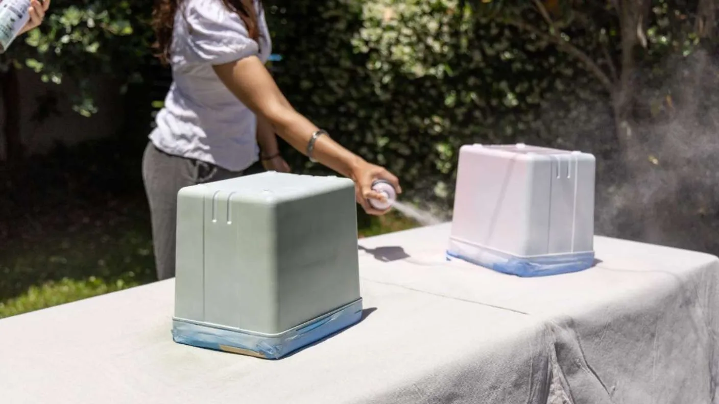 Spraying base coat of White Knight Squirts on esky, one is pastel green, the other pastel pink
