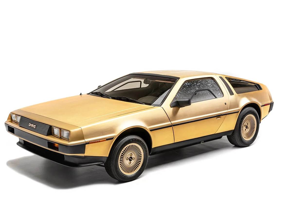 A gold DeLorean DMC-12 sports car with iconic gull-wing doors, showcased against a white background.