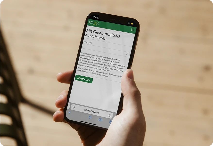Hand, die ein Smartphone hält, auf dem Attexis App, zum Identität bestätigen mittels GesundheitsID, angezeigt wird