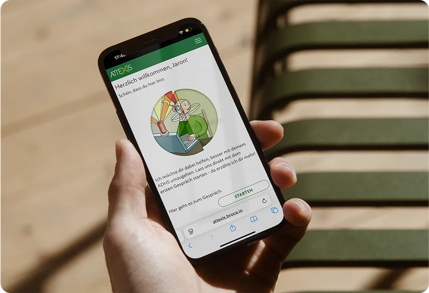 Smartphone wird in Hand gehalten, auf Smartphone wird in der Attexis App willkommen geheißen