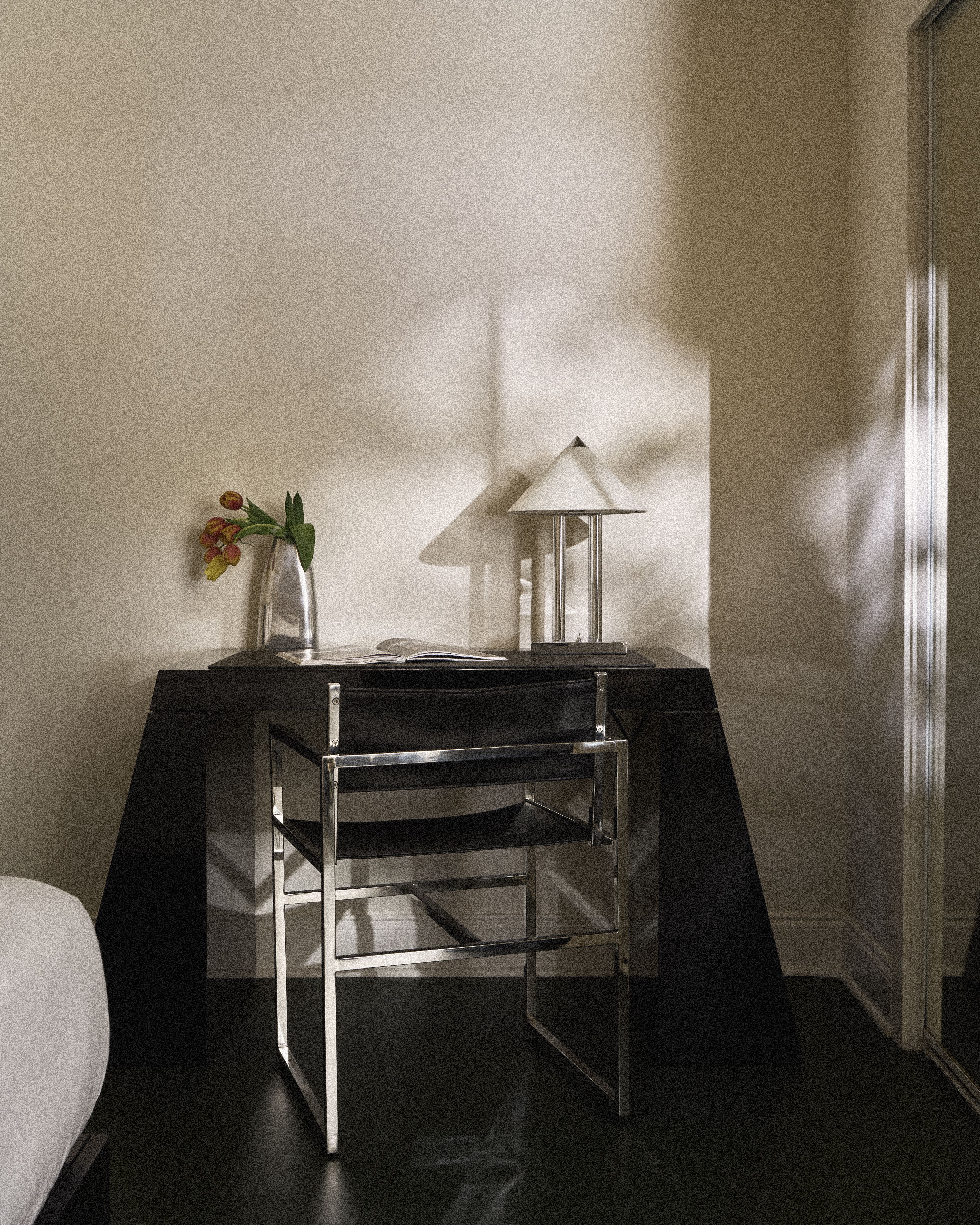 Modern writing desk with chrome chair and designer table lamp inside a Perroquet Hotel guest room.