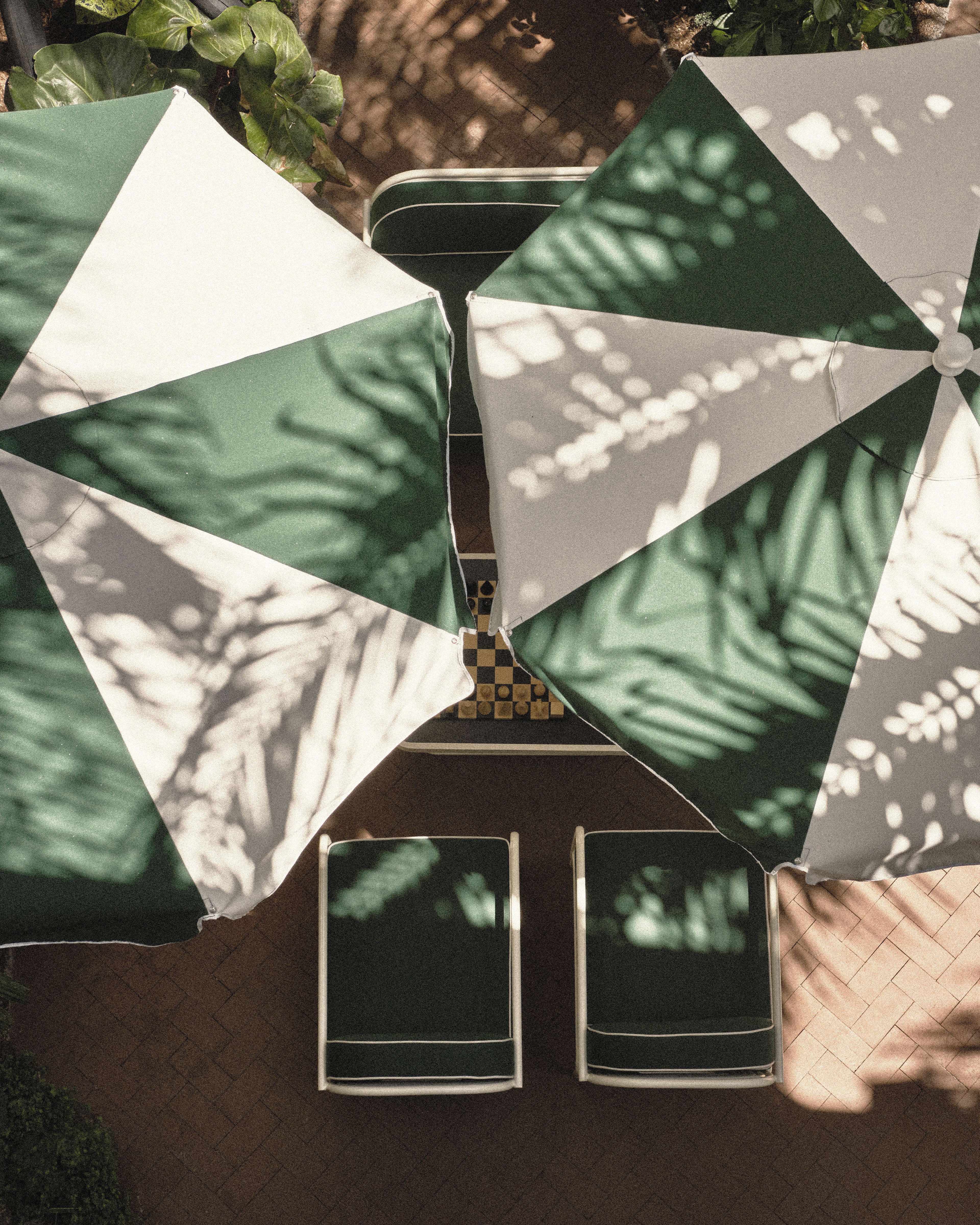 Overhead view of green-and-white umbrellas and courtyard seating surrounded by tropical landscaping at Perroquet Hotel.