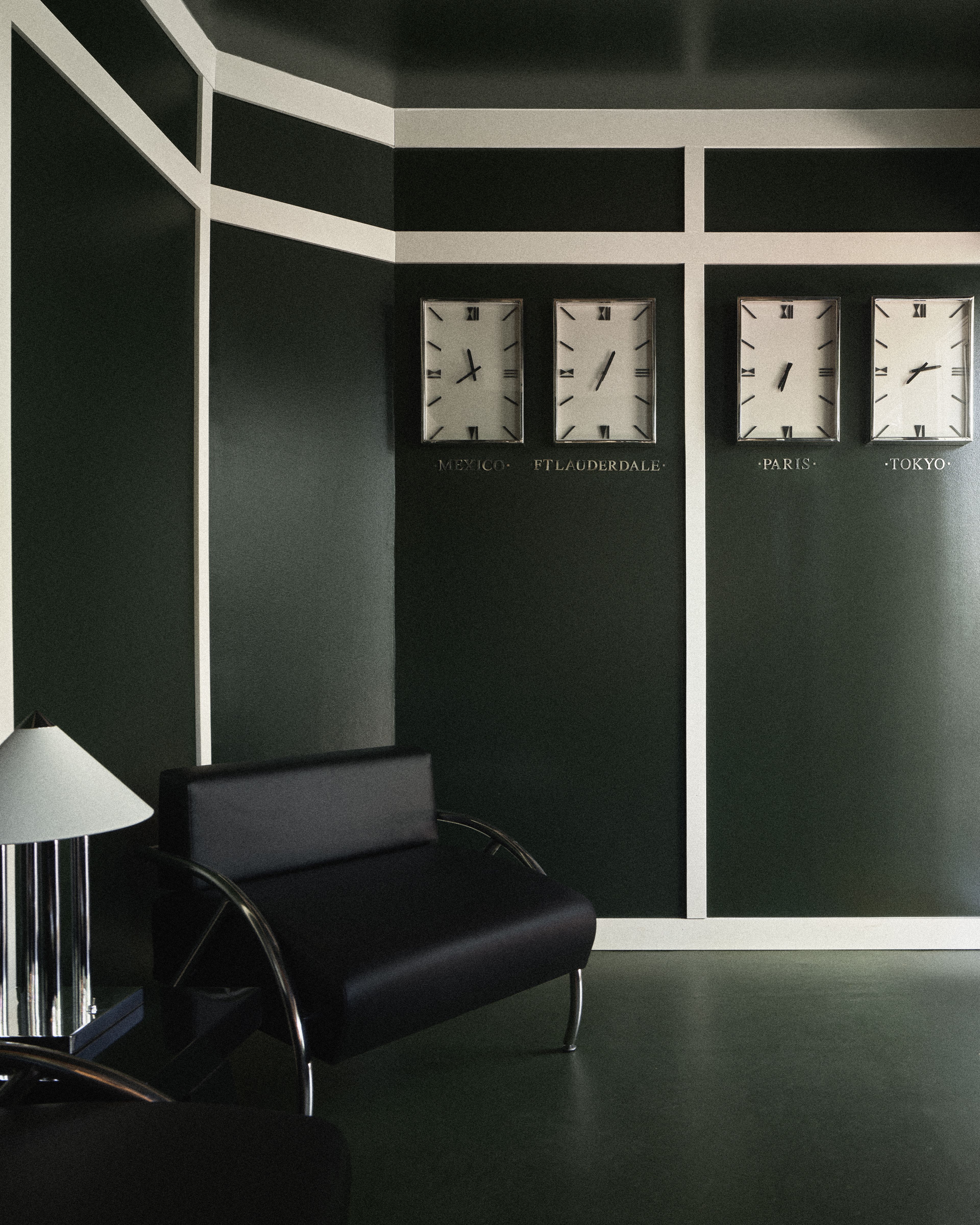 Dark green hotel lobby with world clocks displaying Mexico, Fort Lauderdale, Paris, and Tokyo.