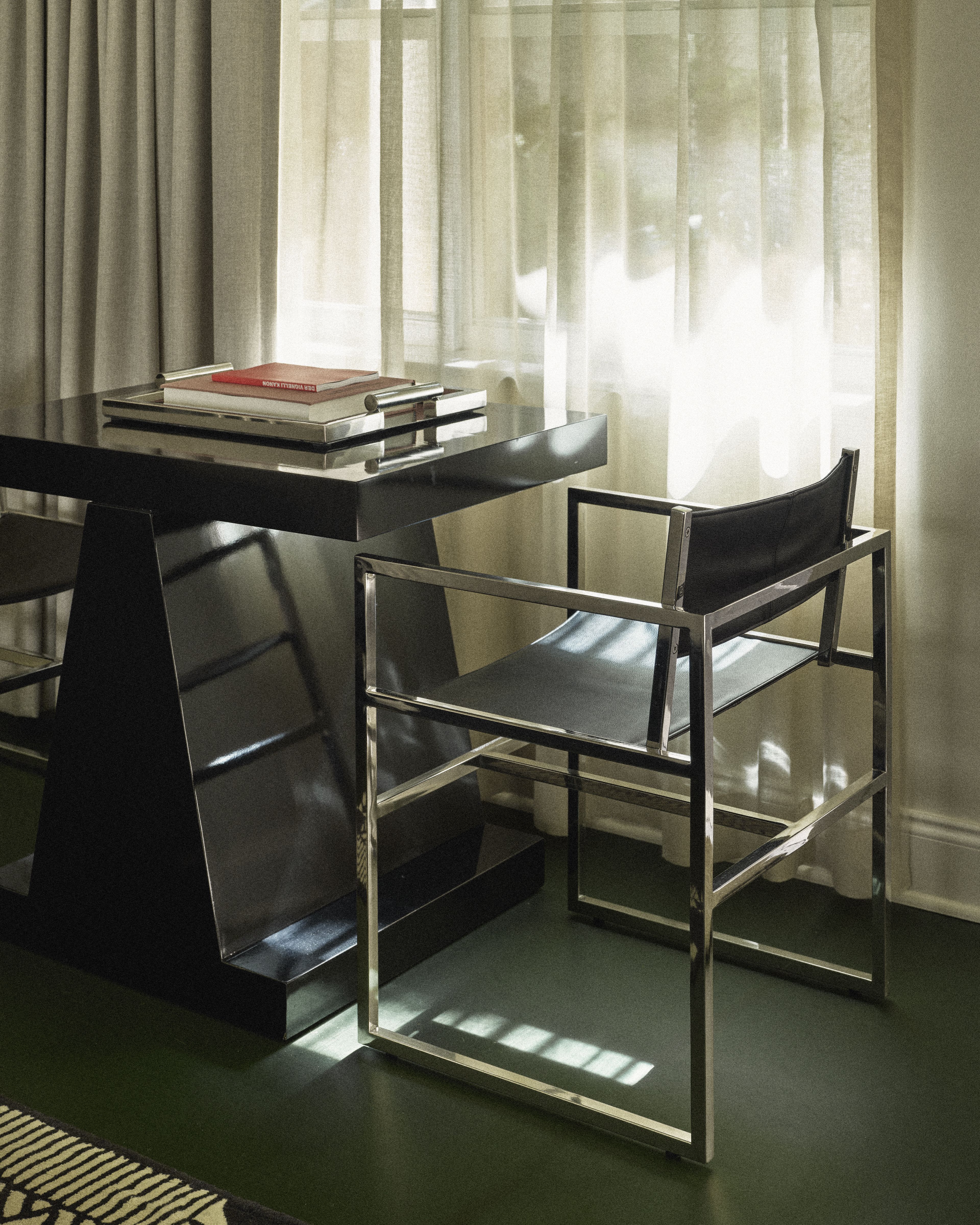 Contemporary writing desk with leather chair and natural daylight in a Perroquet Hotel guest room.
