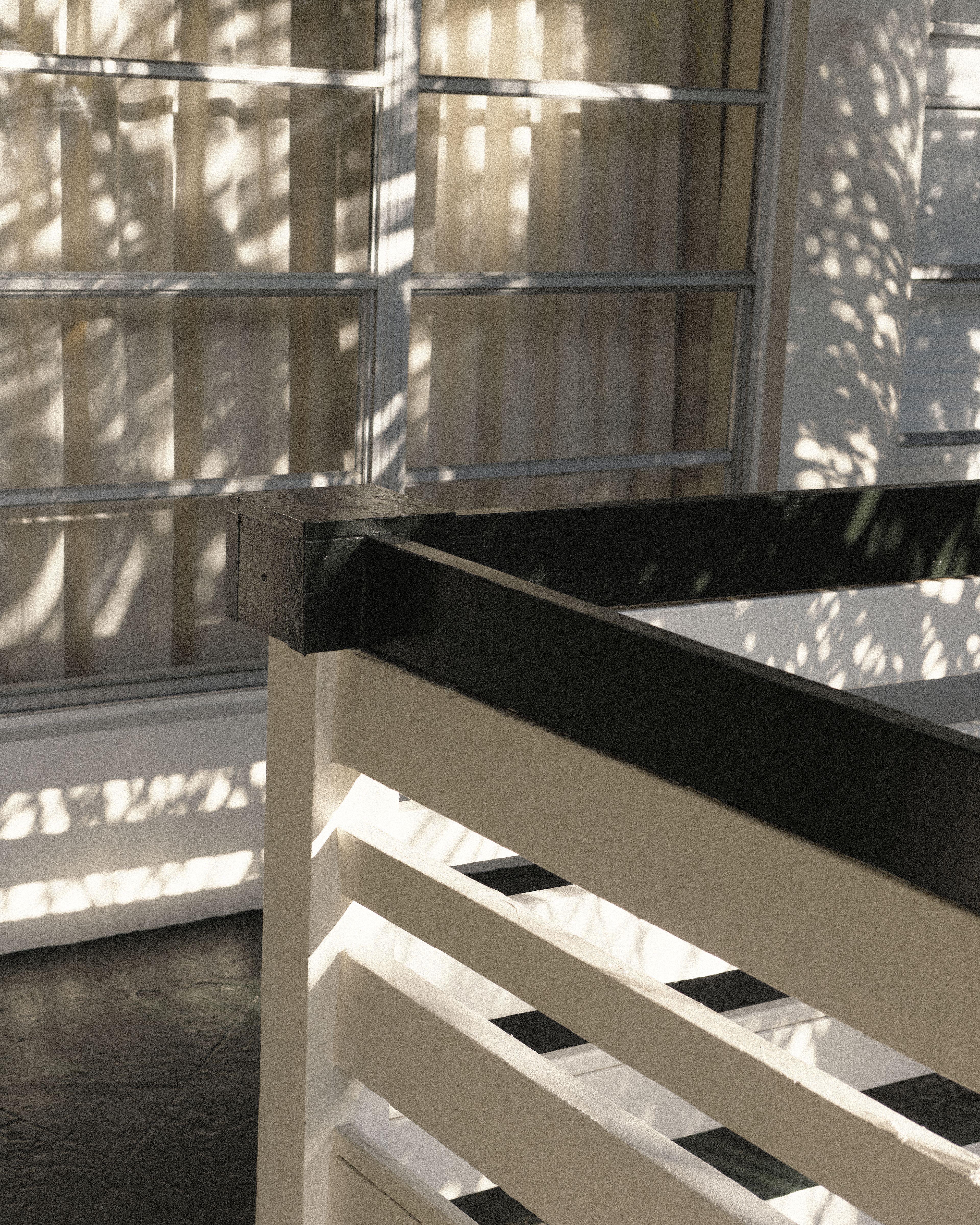 Modern white balcony railing framed by soft palm shadows, highlighting the minimalist architecture of Perroquet Hotel.
