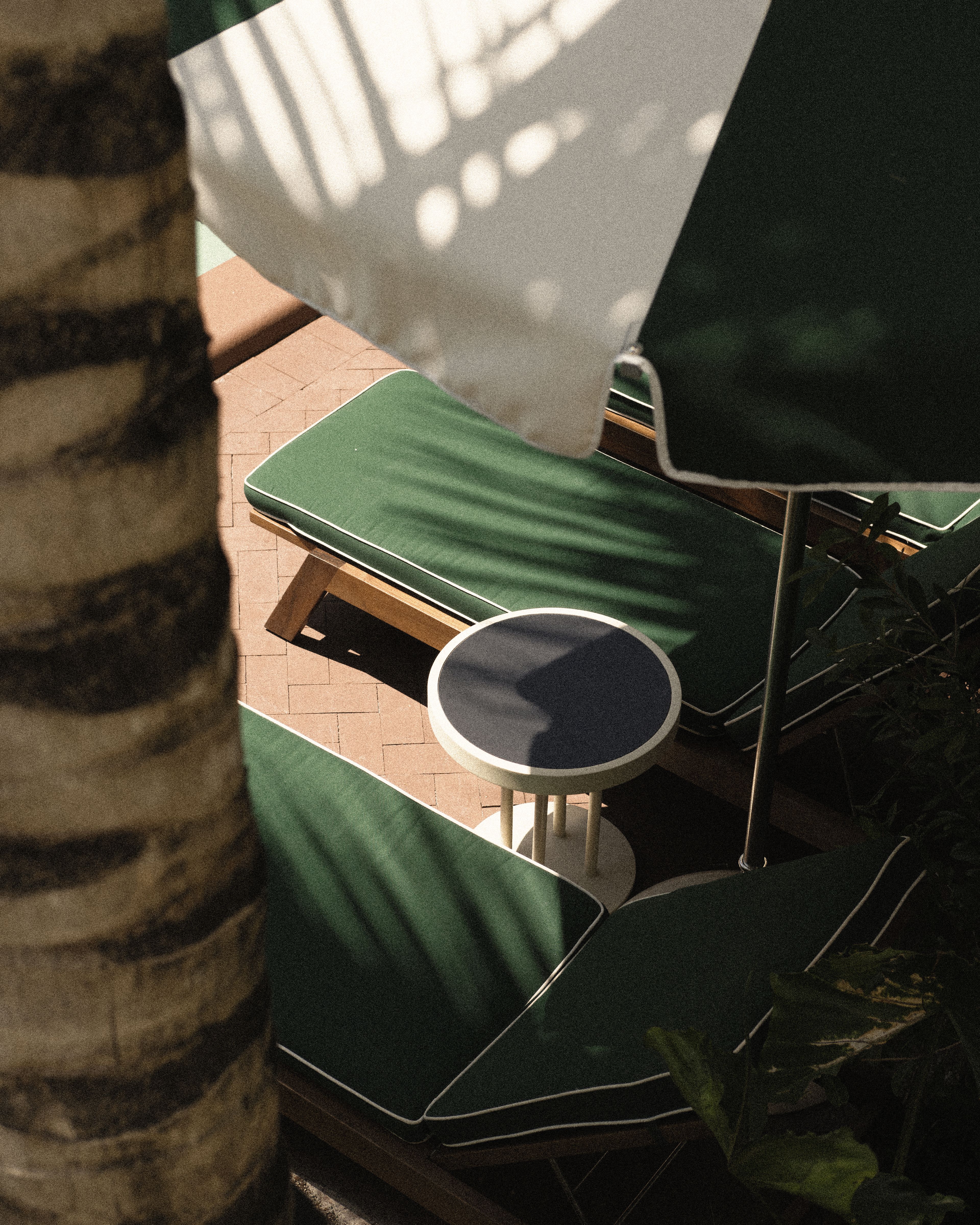 Sun loungers and umbrellas surrounding the boutique hotel pool in a lush tropical courtyard at Perroquet Hotel.