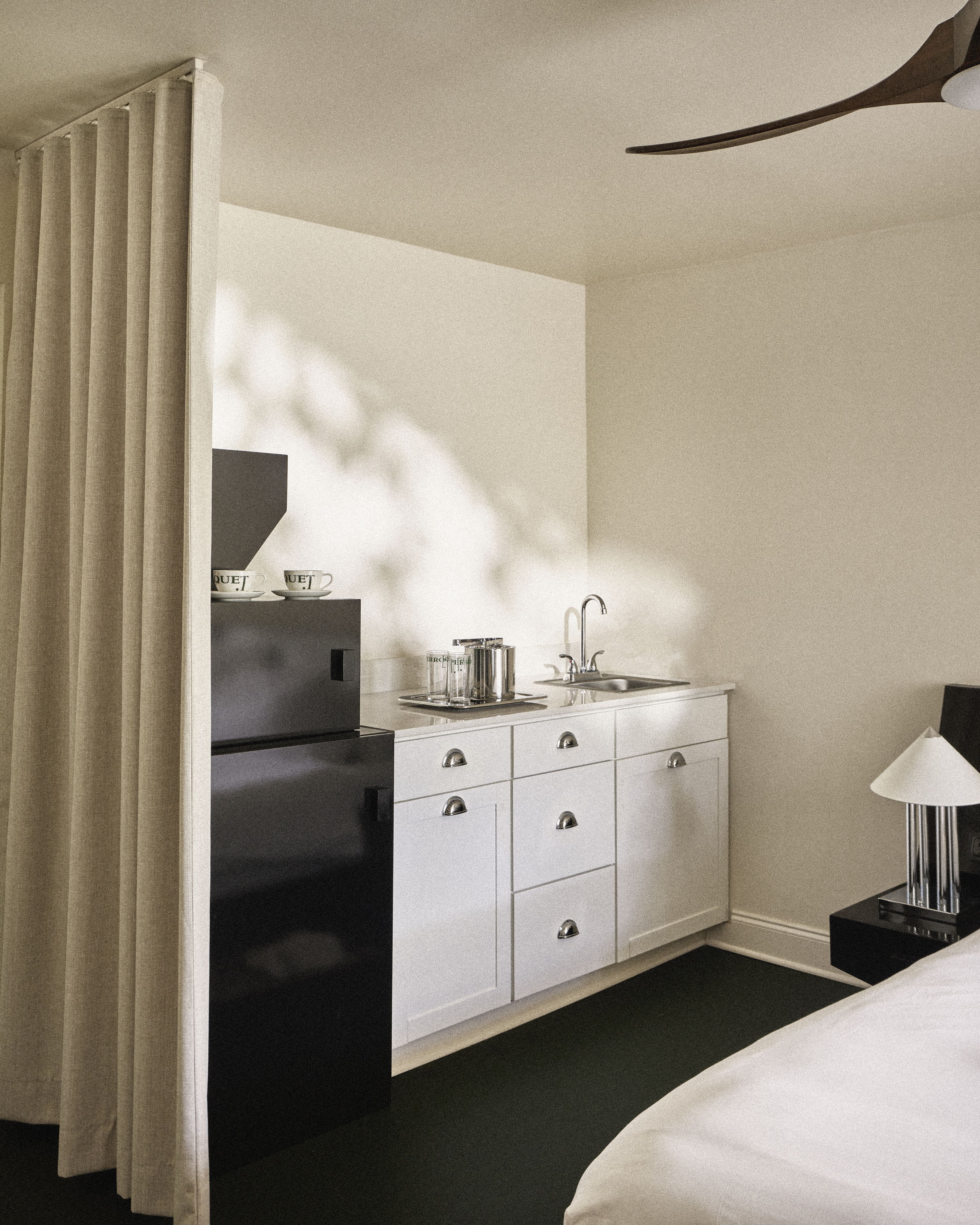 Guest room kitchenette with sink, coffee station, custom cabinetry, and modern finishes at Perroquet Hotel.