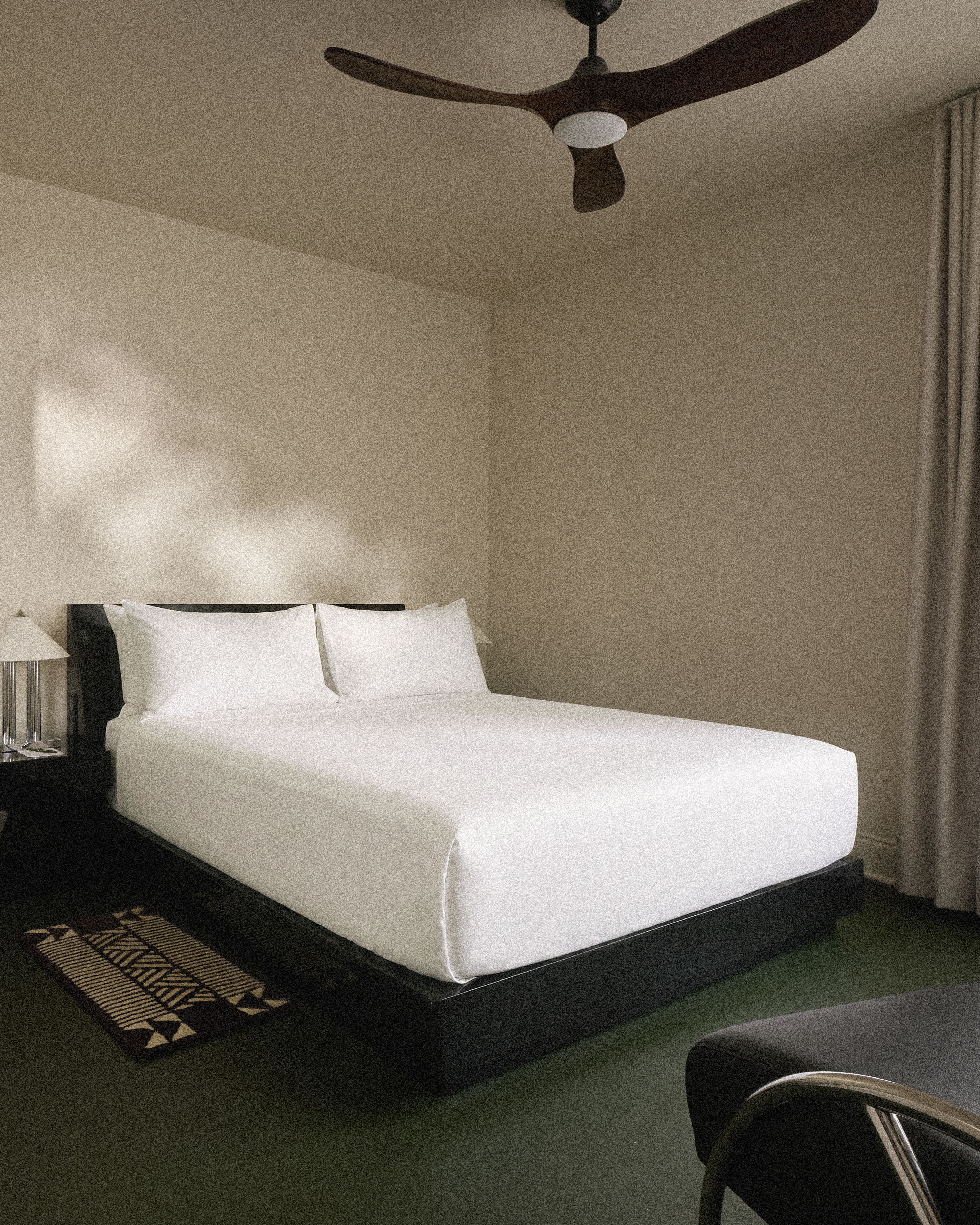 Minimalist king guest room with platform bed, designer lighting, and warm natural light at Perroquet Hotel in Fort Lauderdale.