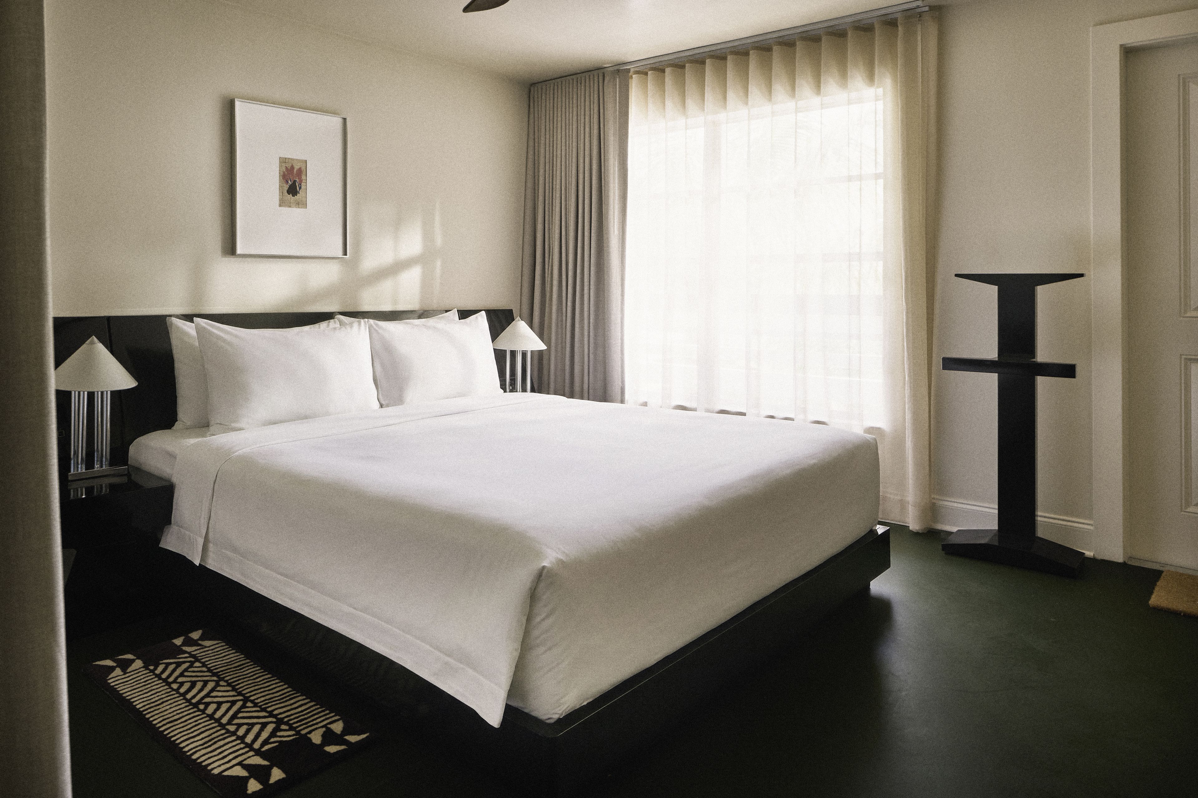 Spacious king guest room with oversized bed, floor-to-ceiling curtains, and contemporary furnishings at Perroquet Hotel.
