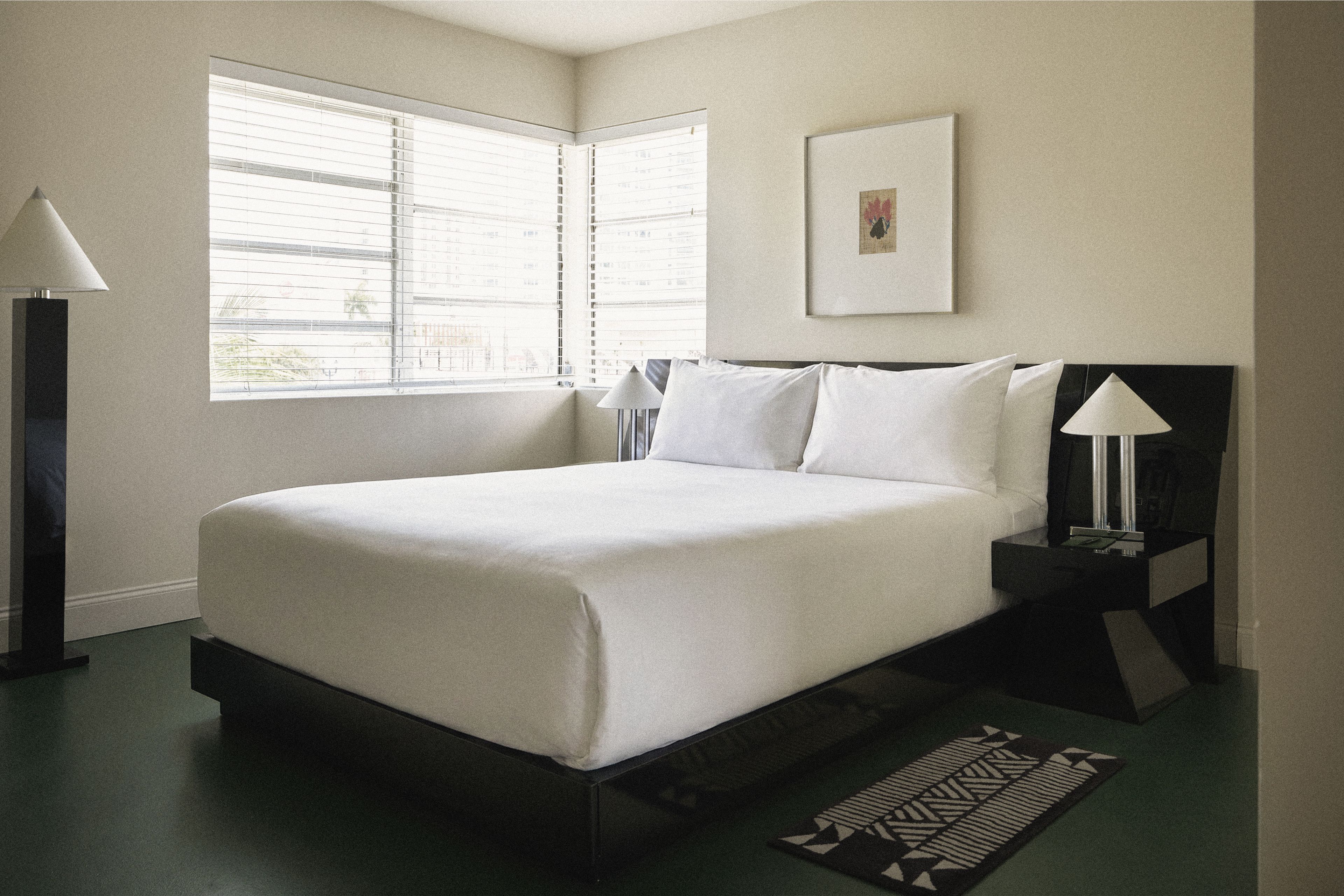 Bright corner king room with expansive windows, platform bed, and contemporary design at Perroquet Hotel.
