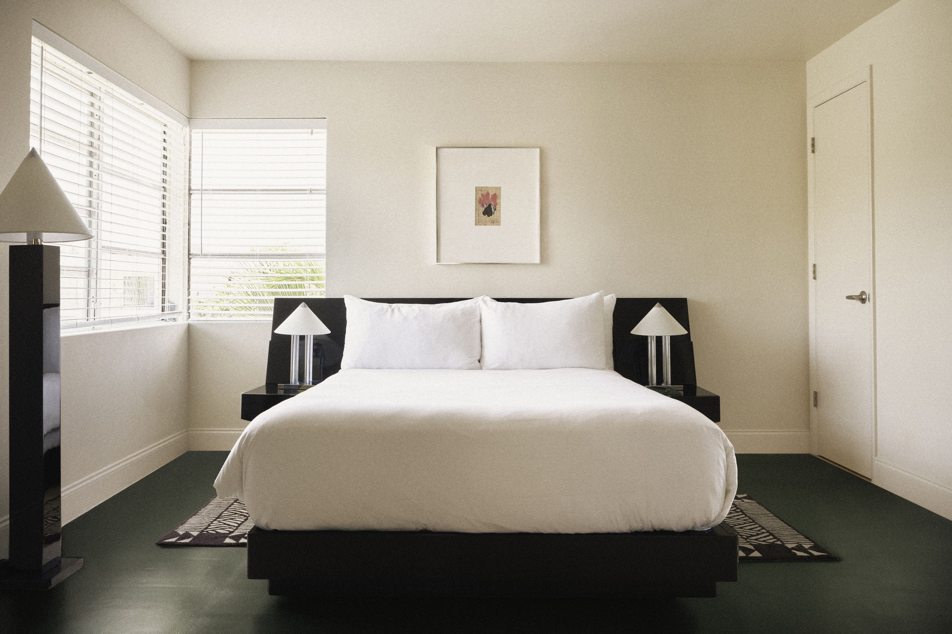Corner king guest room with oversized windows, designer lighting, and minimalist furnishings at Perroquet Hotel.