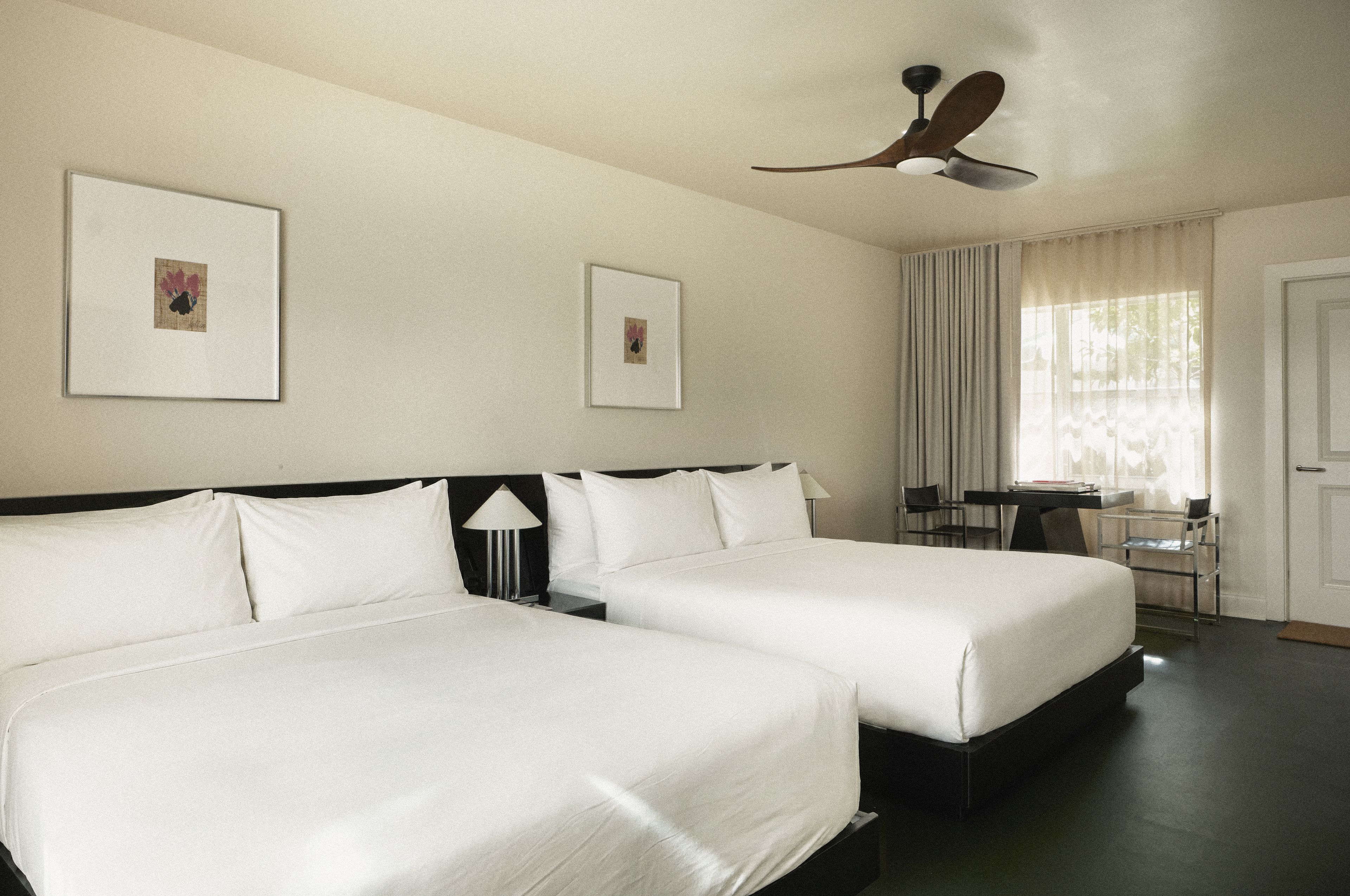 Spacious guest room with two queen beds, modern furnishings, and natural light at Perroquet Hotel in Fort Lauderdale.