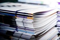 A close-up of a stack of colorful magazines or catalogs, neatly stacked with visible glossy covers and spines.