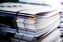 A close-up of a stack of colorful magazines or catalogs, neatly stacked with visible glossy covers and spines.