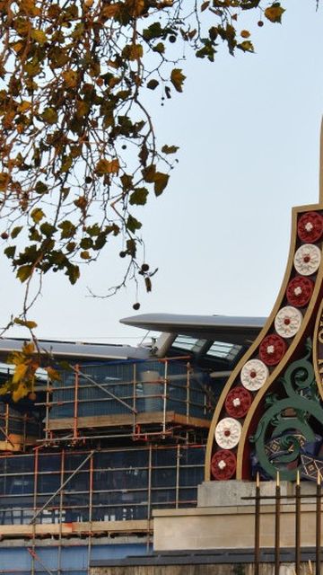 Ornate railway emblem with historical symbols and "London Chatham and Dover Railway" text, framed by autumn branches against a building backdrop.