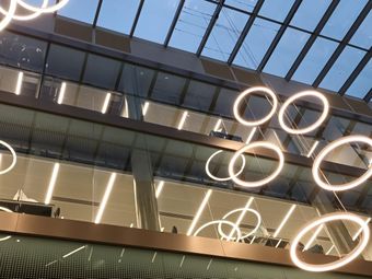 Modern university interior with a glass ceiling, illuminated ring lights, and multi-level views of library spaces.