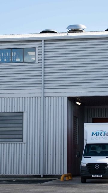 A white van with "MRT Castings" branding is parked in a large, industrial grey building with the same company logo on the facade.