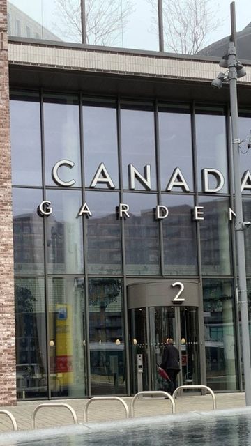Glass entrance of residential Canada Gardens building with "2" displayed over the door, featuring large windows and brick facade.