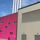Modern industrial building with gray and pink facades, featuring louvre and multiple chimneys against a clear blue sky.