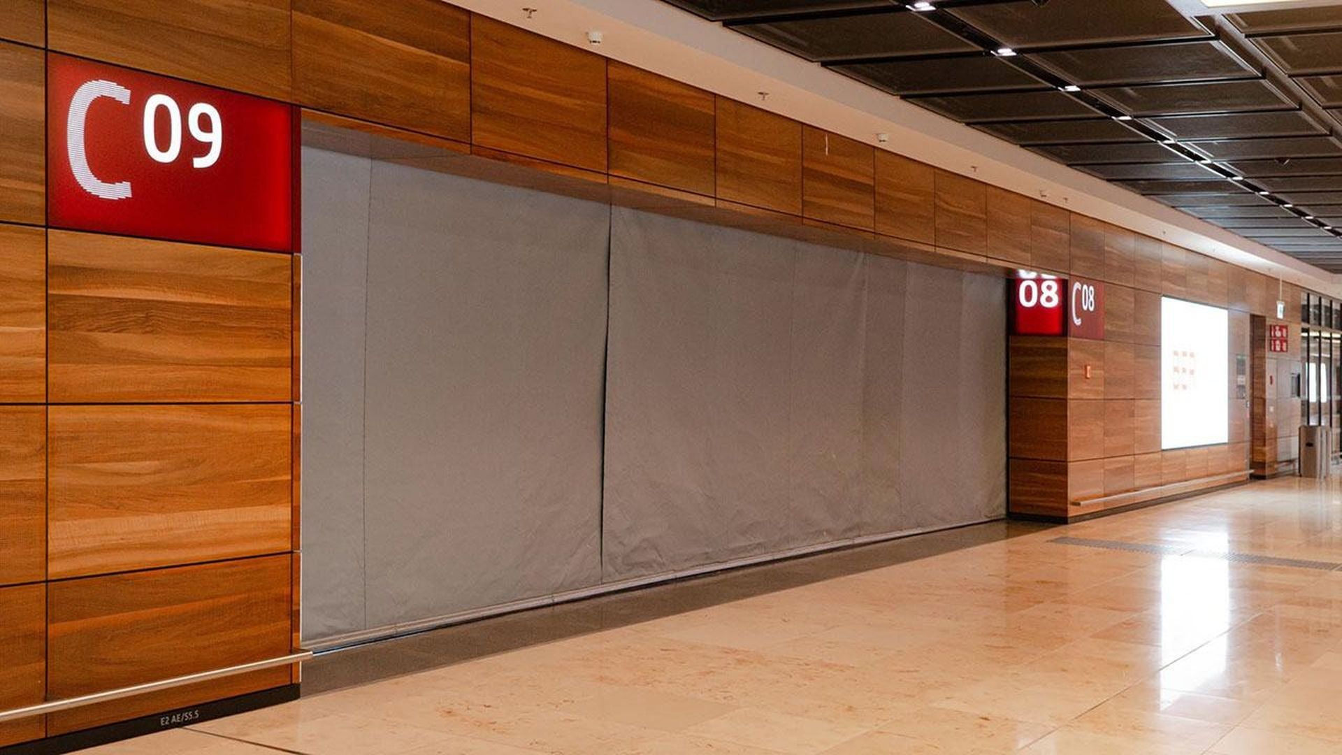 Wood-paneled airport gate area with doors labeled C08 and C09, closed with a gray Smokemaster SM5.