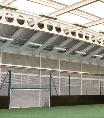Indoor football academy pitch with artificial turf, a small goal, high ceiling, and Colt natural ventilation systems.
