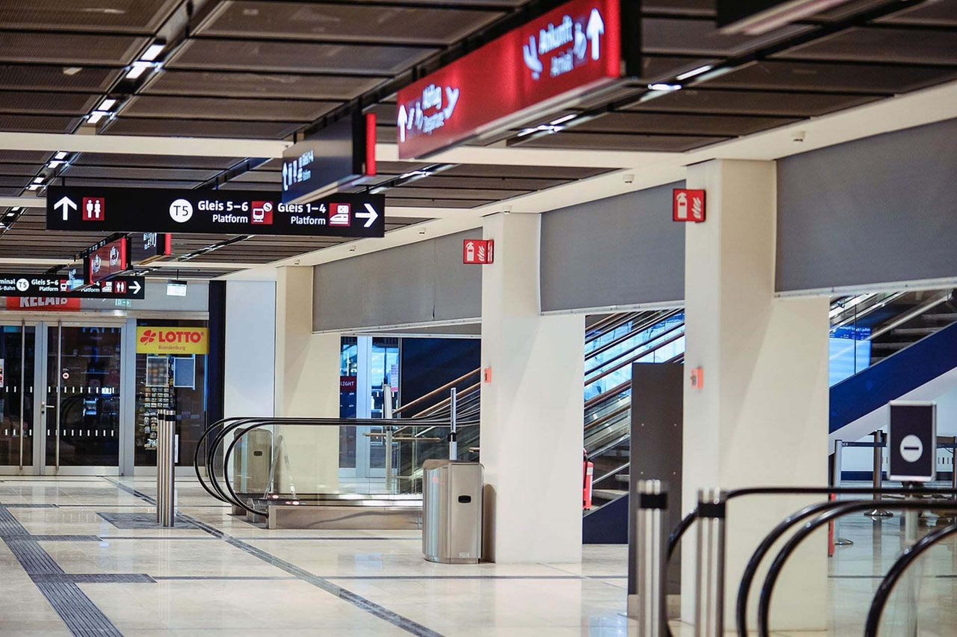 Empty airport concourse with directional signs, escalator, and shops, including a Lotto store, in the background. SmokeMaster SM5 Installed