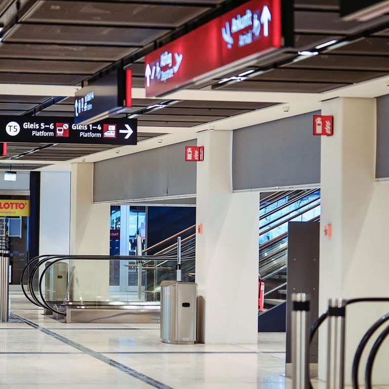 Empty airport concourse with directional signs, escalator, and shops, including a Lotto store, in the background. SmokeMaster SM5 Installed
