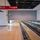 Empty airport terminal with a smoke curtain. Features include a moving walkway, red signs indicating exits and gates A01-36, a large "7" on the wall, and a trash bin in the corner.