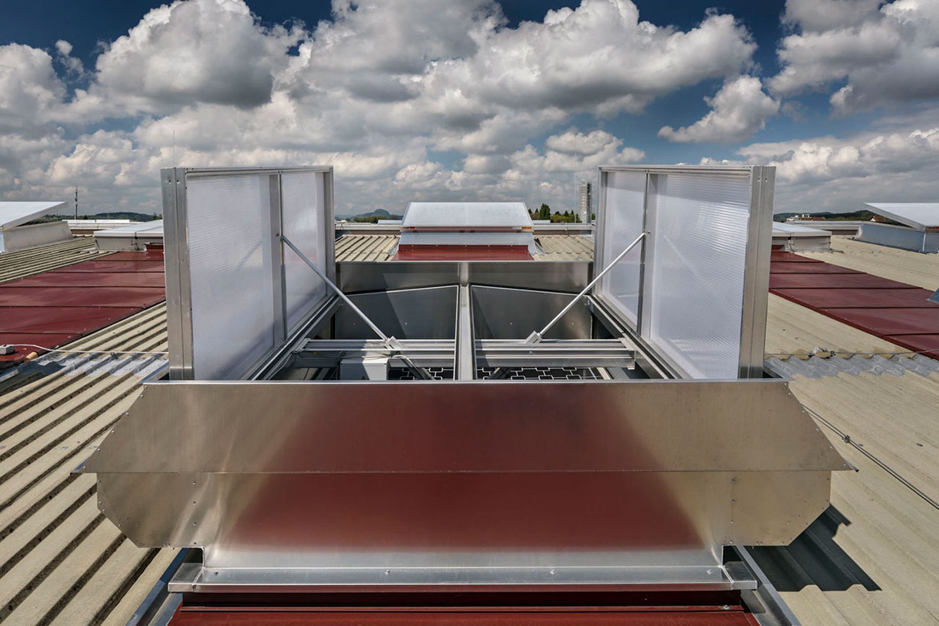 A rooftop smoke ventilation system with open vents, set against a cloudy sky background.