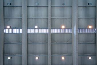 Interior view of a modern industrial ceiling with metal panels, ventilation grates, and evenly spaced lights.