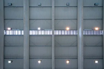 Interior view of a modern industrial ceiling with metal panels, ventilation grates, and evenly spaced lights.