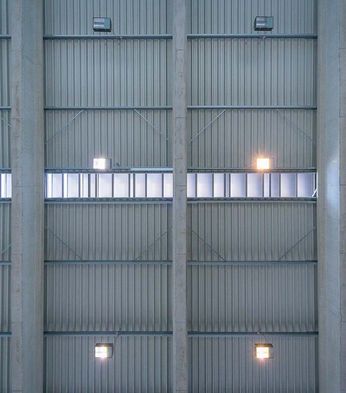 Interior view of a modern industrial ceiling with metal panels, ventilation grates, and evenly spaced lights.