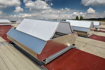 Industrial SHEVS on a flat rooftop under a partly cloudy sky, surrounded by a landscape with trees and distant buildings.