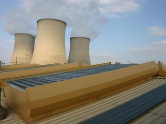 Didcot Power Station with cooling towers emitting steam behind a rooftop with roof ventilators.
