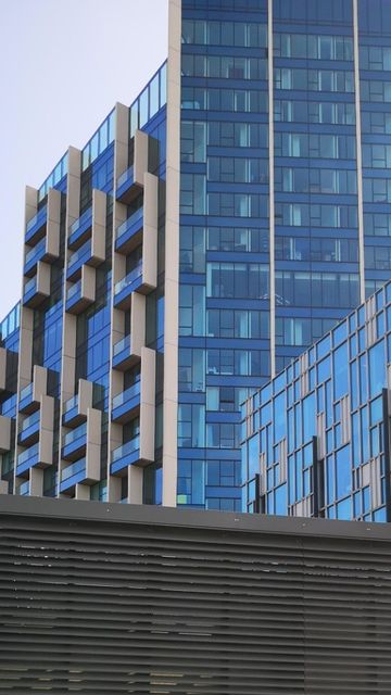 Modern glass skyscrapers with distinctive angular architecture against a clear blue sky. Louvre in foreground