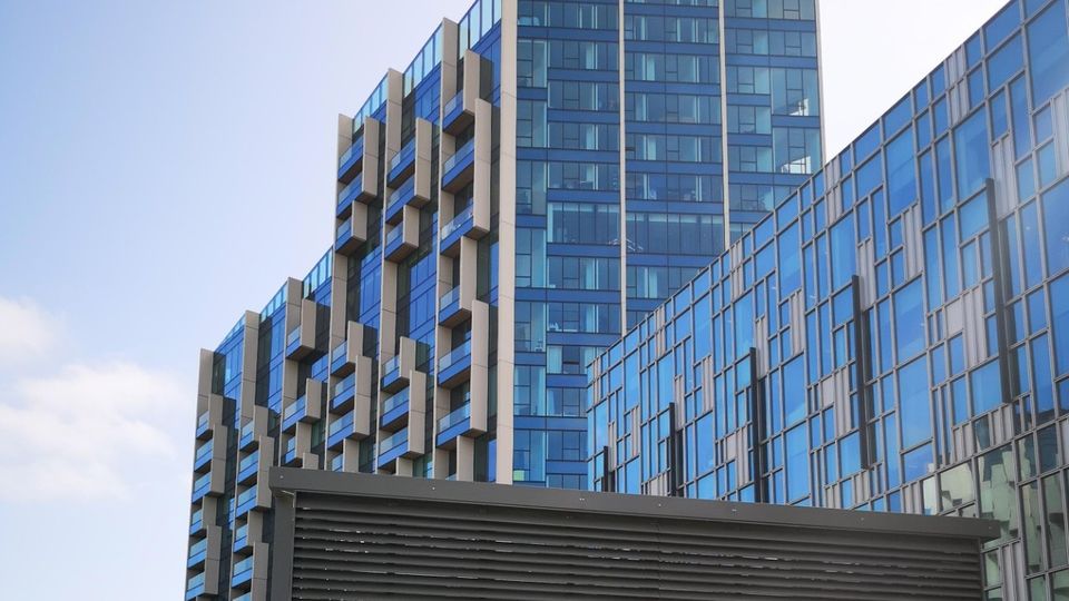 Modern glass skyscrapers with distinctive angular architecture against a clear blue sky. Louvre in foreground
