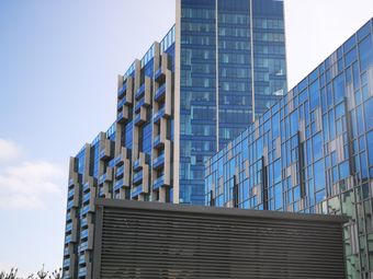 Modern blue glass residential buildings with geometric patterns under a clear sky.