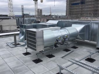 Extraction units on a rooftop under a cloudy sky, with construction equipment and scaffolding visible in the background.