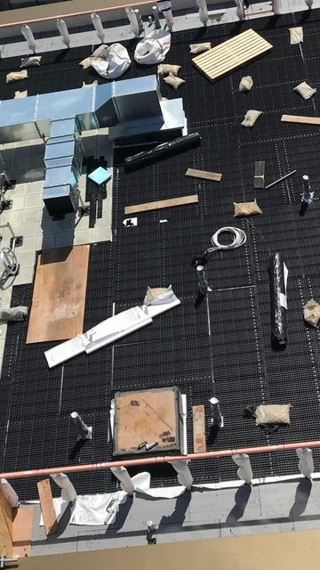 Rooftop view of a building with smoke ventilation systems, insulation, and scattered materials on a grid-like surface.