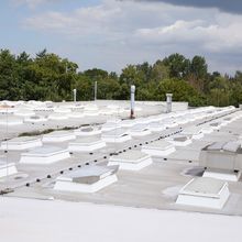 Flachdach mit vielen Lichtkuppeln LK classic von denen manche in Lüftungspositionen stehen und manche Eckleitwände haben.