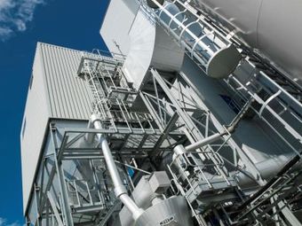 Industrial facility with metal structures and pipes under a clear blue sky.