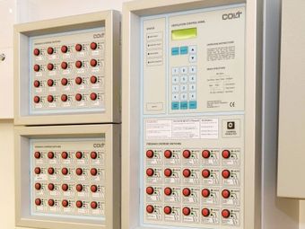 Control panels with numerous red and white buttons, arranged in grids, alongside a unit with a keypad and small digital screen.