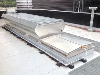 A rooftop smoke vent system with a metallic rectangular design and a raised hinged panel.