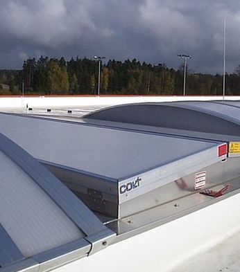Closed SHEVS on a rooftop, underneath a cloudy sky, with trees in the background.